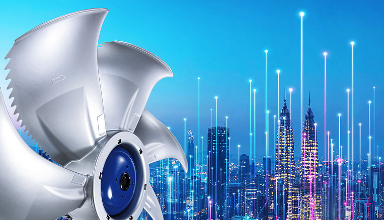 Grauer ZIEHL-ABEGG Ventilator mit blauem Motor vor einer Skyline bei Nacht