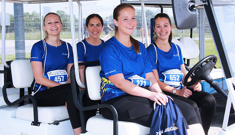  Lächelnde ZIEHL-ABEGG Mitarbeiterinnen mit blauem Firmenshirt in einem Golfcart
