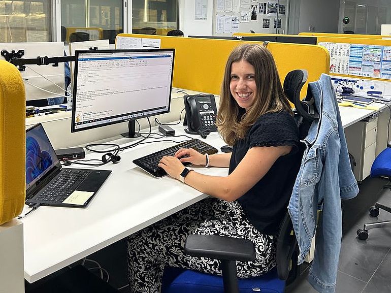 Frau am Schreibtisch vor einem Computer in Dubai lächelnd